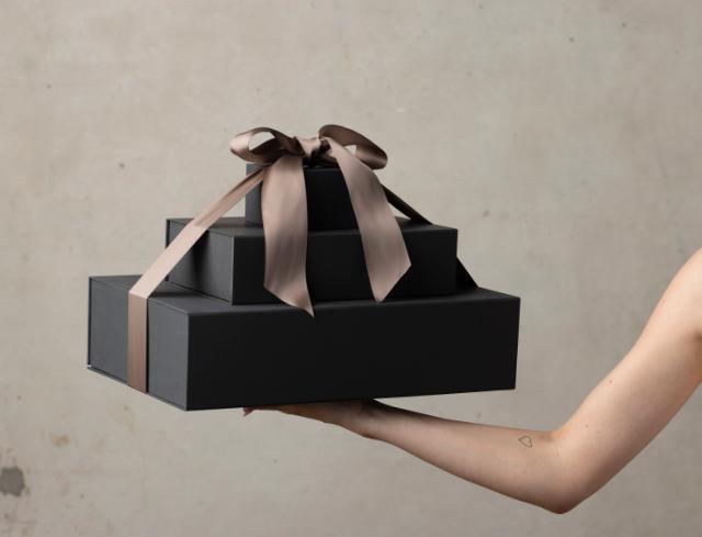 A hand gracefully holding a beautifully wrapped gift box. The hand is delicately positioned, showcasing the anticipation and excitement of giving or receiving a present. 